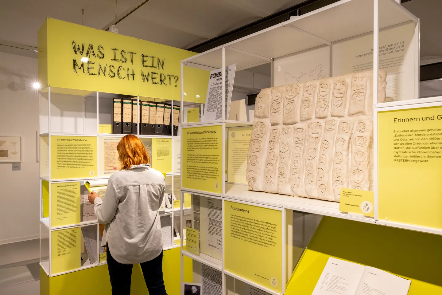 Ein Regal, betitelt mit dem der Frage. „Was ist ein Mensch wert?“, darin Texte und Ausstellungsstücke